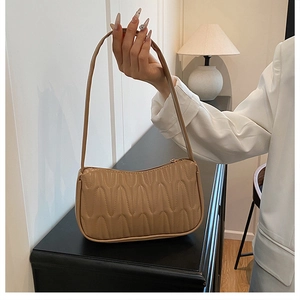 Detail shot of mini French style underarm bag with unique wavy quilted texture in beige