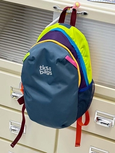 Detail view of colorful nylon backpack showing mesh side pocket and zipper closures