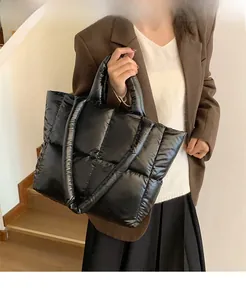 Detail of black quilted puffer tote bag featuring glossy finish and thick shoulder straps