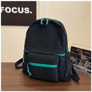 Close-up of black nylon backpack featuring mint green zippers and side water bottle pocket