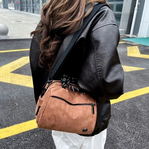 Brown faux suede crossbody bag with woven handle shown on model in street setting
