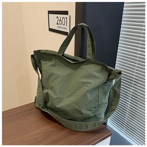 Detail view of large olive green nylon tote bag with crinkled texture on wooden surface