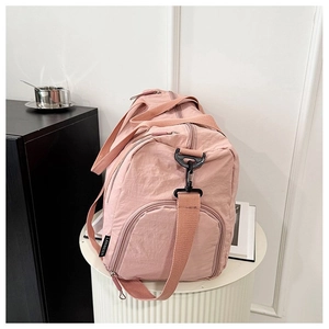 Close-up of pink nylon travel bag featuring side zipper pocket and brand woven label