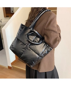 Close-up of black quilted puffer tote bag with glossy finish and dual handle design