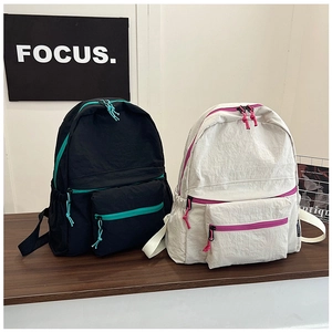 Detail of color-block nylon backpacks with contrasting zippers and multi-pocket design