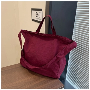 Detail of burgundy oversized tote bag with wrinkled texture on a wooden table