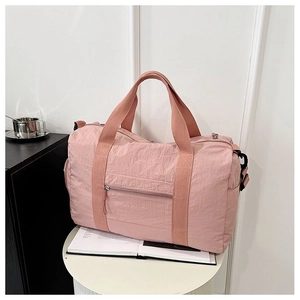Detail of pink nylon travel bag with anti-scratch texture and reinforced webbing handle