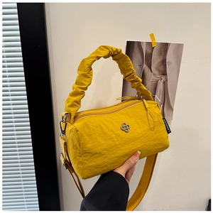 Detail of ginger nylon barrel bag featuring a unique gathered handle and metal flower buckle