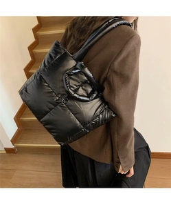Close-up of black quilted tote bag with glossy finish and large puffer square patterns