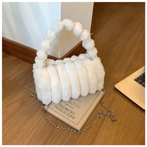 Détail du sac polochon en fausse fourrure blanche avec poignée à pompons et chaîne argent