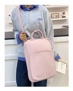 Dettaglio della borsa capiente in nylon rosa portata a spalla da una modella in posa