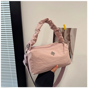 Detail of pink nylon handbag featuring ruched handle and flower shaped metal logo