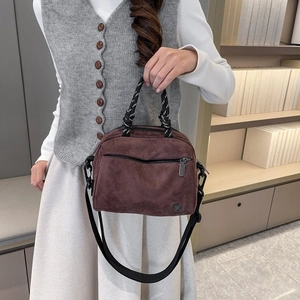 Detail of dark brown suede crossbody bag with bicolor knotted handle and metal logo
