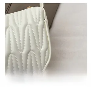 Detail shot of the white quilted shoulder bag showing wavy pleated texture and gold zipper