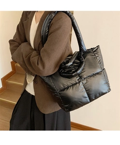 Quilted puffer tote bag in black nylon shown on a woman wearing a brown blazer
