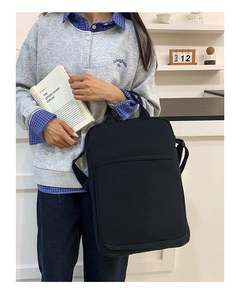 Donna con borsa tote in tela nera e tasca frontale con cerniera in un ambiente luminoso