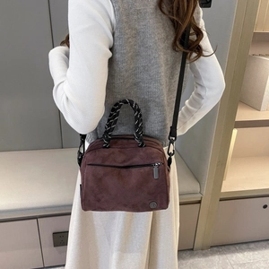 Brown faux suede crossbody bag with metal zipper and rope handle on modern home backdrop