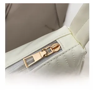 Macro shot of minimalist gold zipper and ivory quilted leather on a shoulder bag