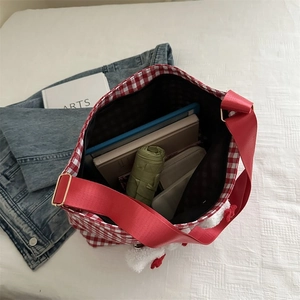Macro shot of large capacity red checkered canvas bag with daily items inside