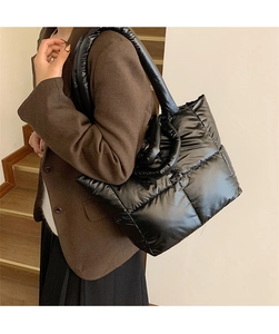 Close-up of black quilted puffer tote bag in shiny waterproof nylon with wide padded strap
