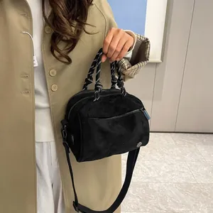 Detail of black suede multi-zip crossbody bag with striped woven handles on a model