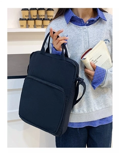 Dettaglio borsa in tessuto Oxford nero con tasca frontale e tracolla regolabile