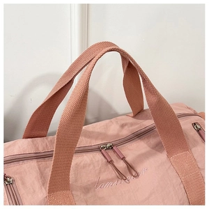 Detail of pink nylon sports bag showing embroidered text and smooth zipper closure