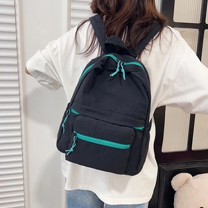 Minimalist black backpack with teal zipper detail shown on model from the back