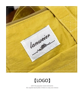 Close-up of yellow canvas tote bag with woven brand label and detailed stitching texture