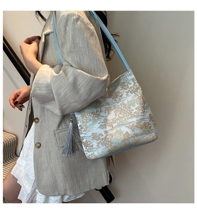 Detail of light blue shoulder bag featuring traditional Chinese embroidery and silk tassel