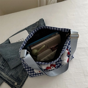 Macro shot showing blue checkered canvas bag interior with daily essentials and doll