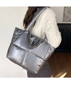 Detailed view of silver quilted tote bag made of metallic fiber fabric worn by a model