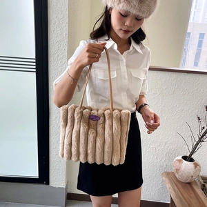 Dettaglio della borsa tote beige in pelliccia sintetica con texture a righe e tracolla in pelle