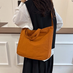 Minimalist orange large capacity canvas tote bag worn by a model in a casual setting