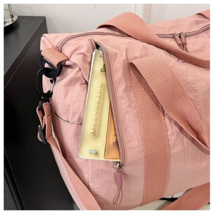 Detail of a light pink waterproof nylon travel bag showing a side zipper pocket and texture