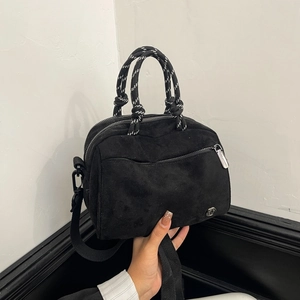 Detail of matte black crossbody bag featuring unique black and white knotted rope handles