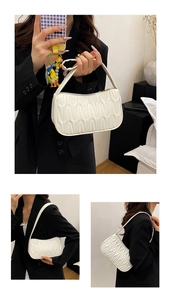 Close-up of white quilted hobo bag with ripple texture and golden zipper hardware