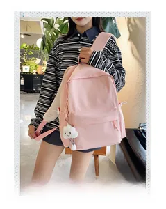 Detailed view of a pink minimalist backpack with a white cloud plush charm and side drawstring pocket