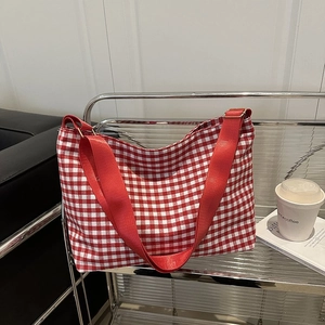 Detail of red and white checkered canvas bucket bag with wide red shoulder strap