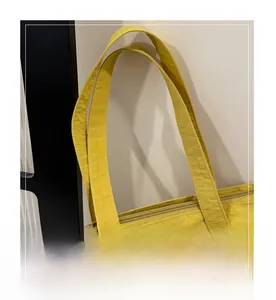 Detail of yellow tote bag showing reinforced stitching and durable fabric texture