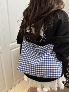 Detailed shot of large blue checkered canvas bucket bag on shoulder with casual style