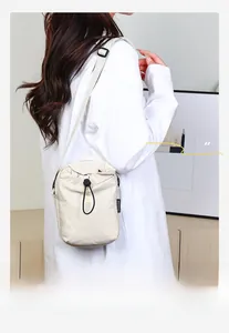 Dettaglio della borsa a tracolla in nylon beige con coulisse nera ed etichetta tessuta