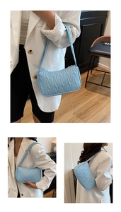 Detail view of light blue underarm bag with vertical quilted wave stitching pattern