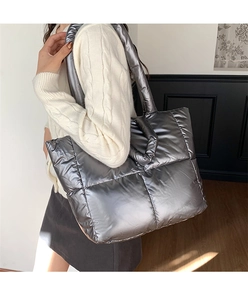 Close-up of metallic silver quilted tote bag with padded texture and wide shoulder strap