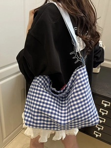 Detailed texture of blue and white checkered canvas tote bag with wide shoulder strap
