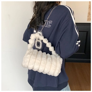 Détail du sac à main en peluche blanche avec poignée sphérique décorative et chaîne métallique