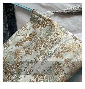 Macro shot of jacquard landscape embroidery and white jade tassel on the shoulder bag