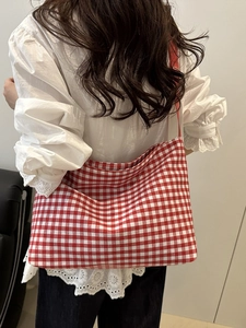 Detail of red gingham canvas tote bag showing the textured fabric and shoulder strap