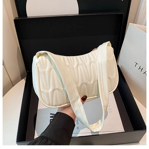 Detail of cream white underarm bag with vertical quilted pleated texture and wide strap