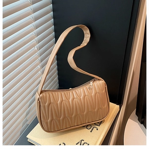Detail of the pleated texture and zipper on the beige French baguette shoulder bag